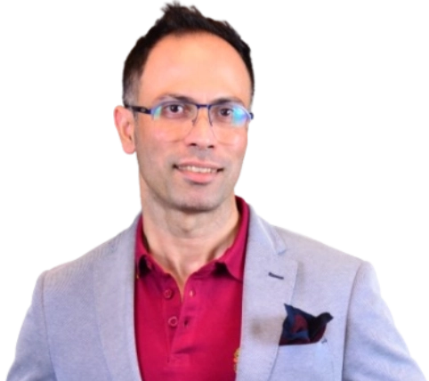 Man with short dark hair and glasses wearing a light gray blazer, red polo shirt, and navy pocket square, smiling at camera.