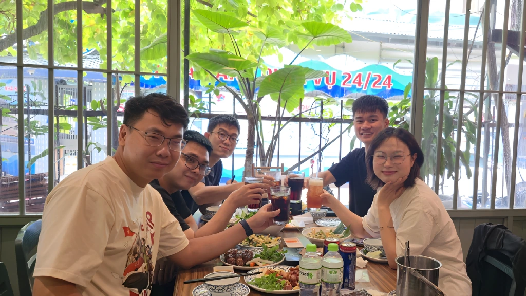 Team members sitting together at a table, raising their drinks and enjoying a shared lunch