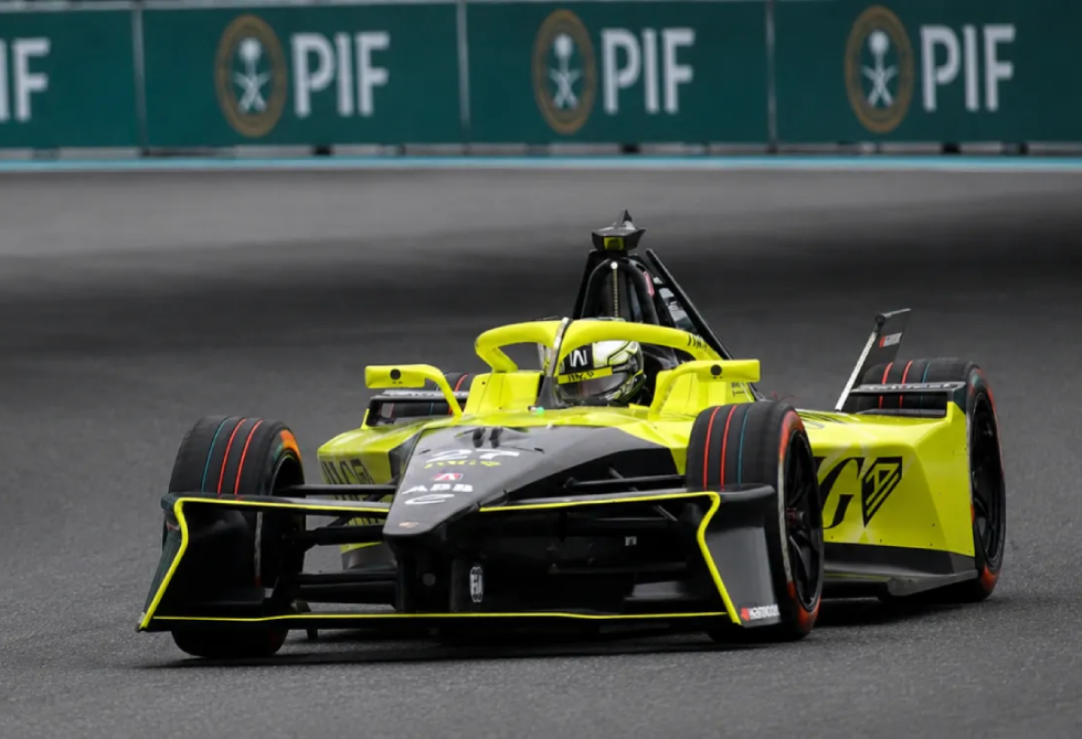 Yellow and black open-wheel race car speeding on a track with PIF banners in the background, ready for a lap or race.