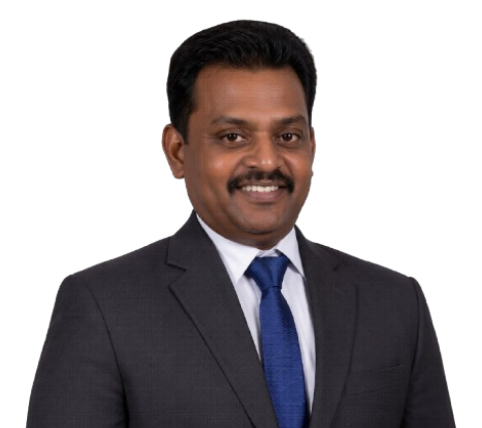 Professional headshot of a man in a dark suit, white shirt, and blue tie, smiling at the camera